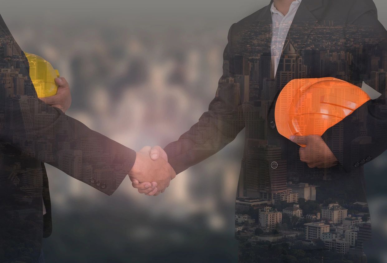 Two men shaking hands in front of a building.